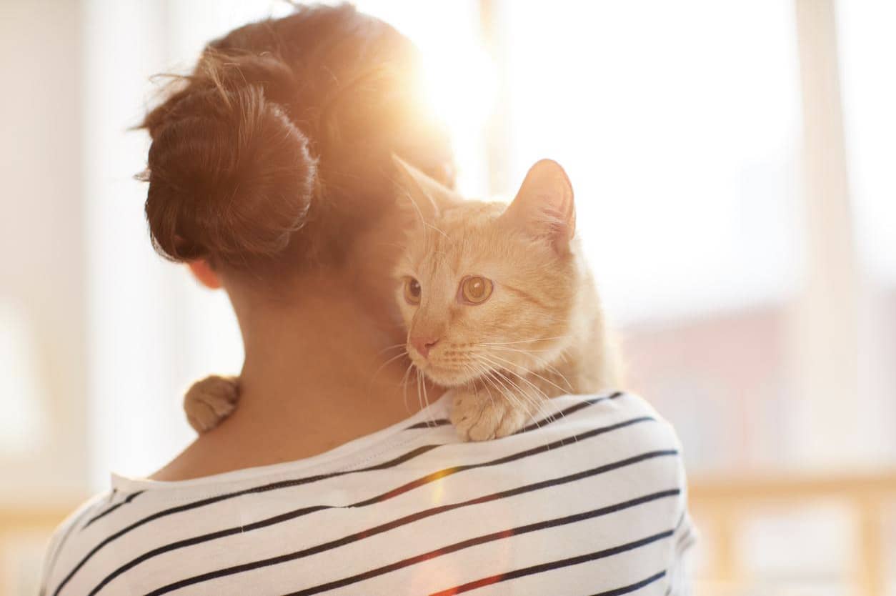 A woman with her back turned to the camera holding a cat