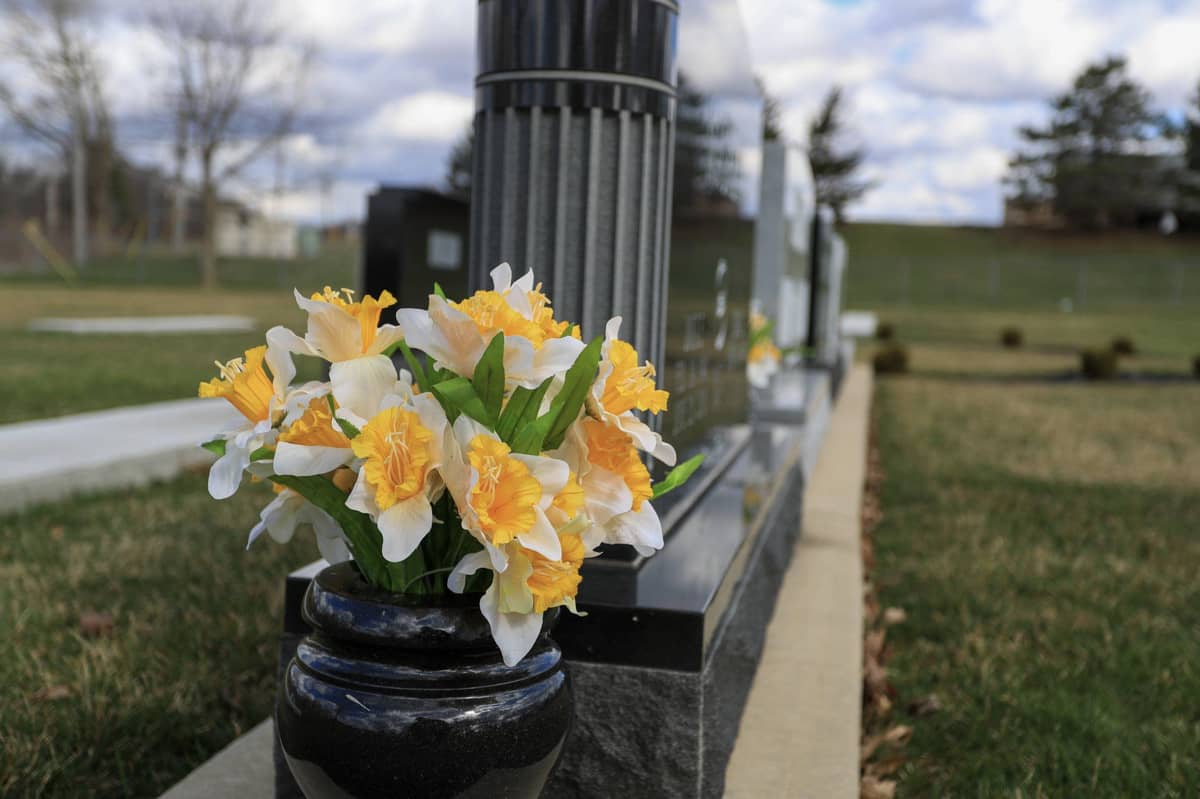 White and yellow flowers by tombstone