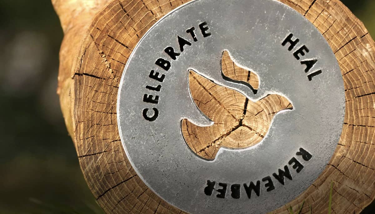A silver plaque with a bird cut out and the words "Celebrate, heal, remember"