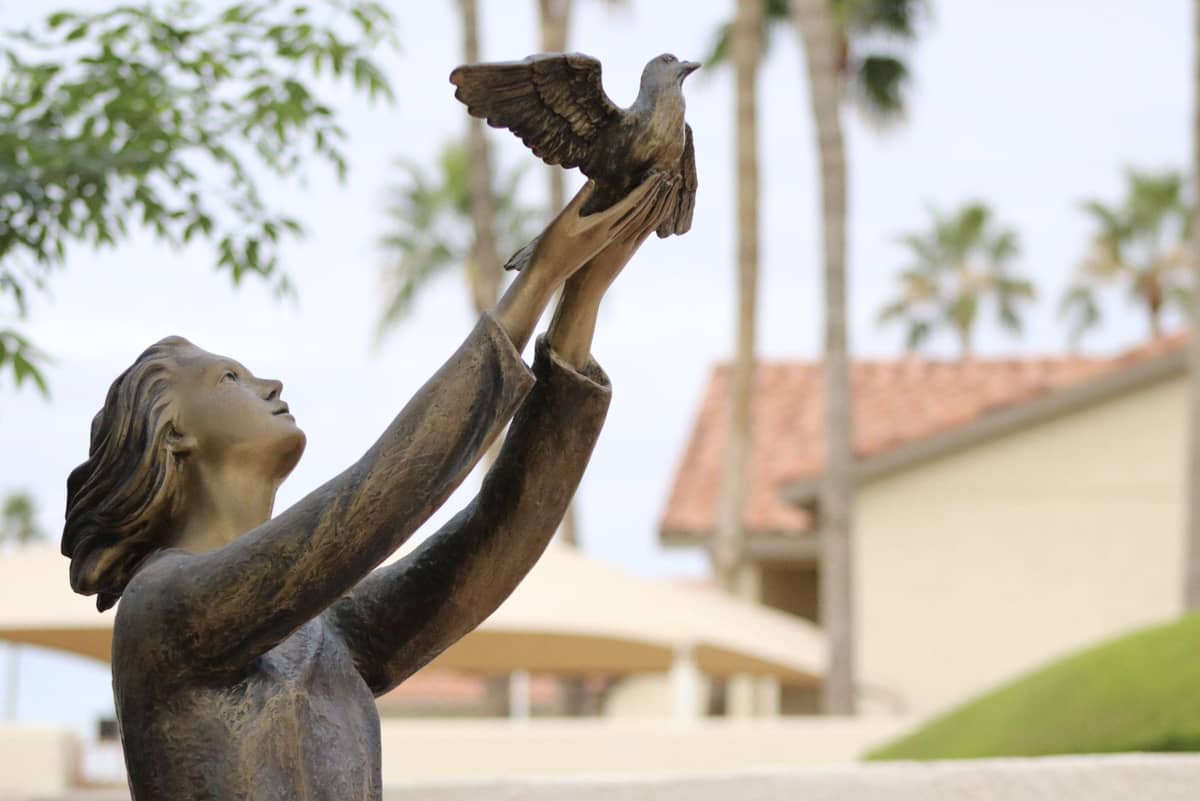 A statue of a woman holding a bird (holding up as if releasing the bird)