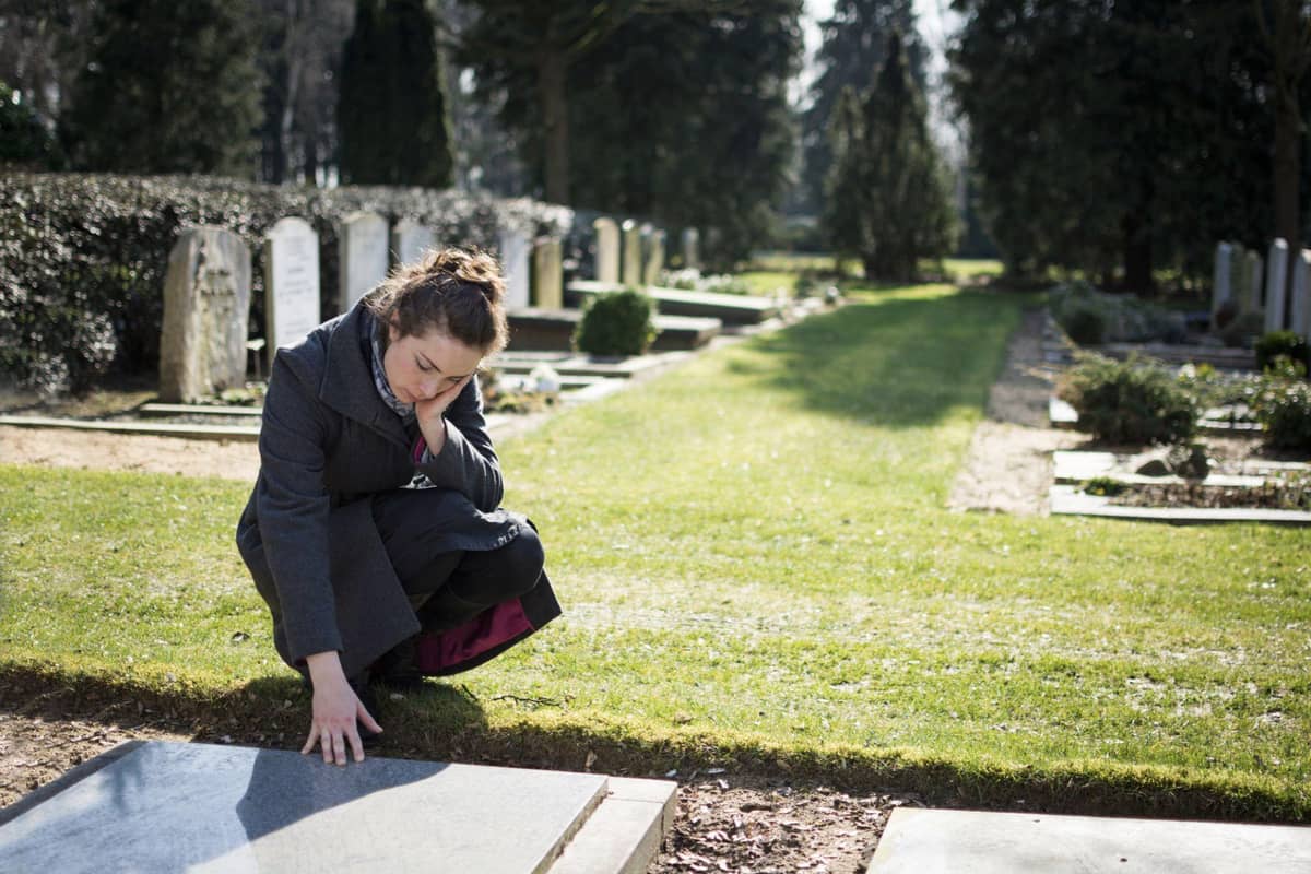 A woman touching a grave marker