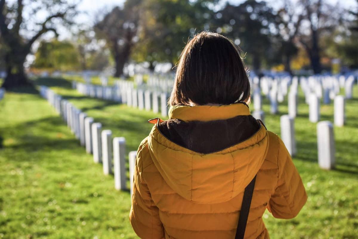 The back of a woman walking through a cemetery